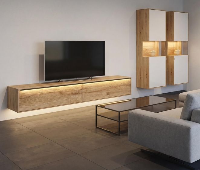 Gemütliches Wohnzimmer mit einem wandhängenden Lowboard aus Holz und weißen Fronten, ergänzt durch ein passendes Wandregal. Der Flachbildfernseher steht auf dem Lowboard, während ein graues Sofa und ein Glastisch mit schwarzem Metallgestell den Sitzbereich gestalten.